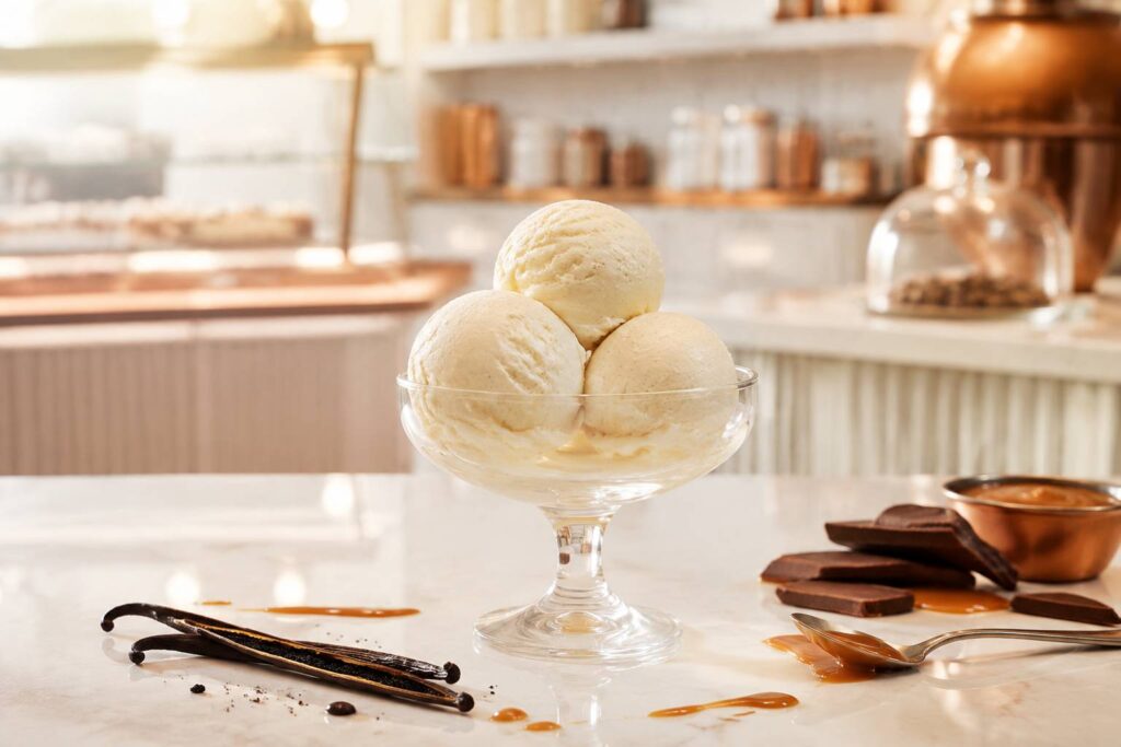 Boules de glace à la vanille crémeuse en coupe avec une gousse de vanille